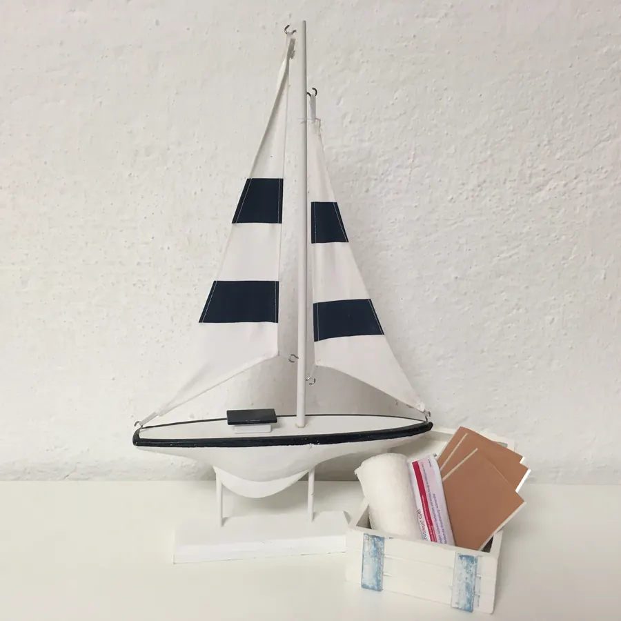 Modell-Segelboot neben Verbandsmaterial und Pflastern für die Reiseapotheke